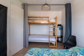 Ein Schlafsaalzimmer mit Etagenbetten, einem Schreibtisch, einem Stuhl und einer Pendelleuchte.