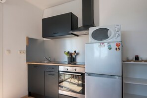 Une cuisine compacte équipée d’un four à micro-ondes, d’un four traditionnel et d’un lave-vaisselle encastré.