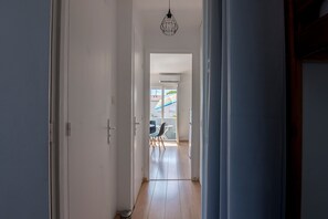 Ein Flur, der zu einem Balkon mit Blick auf ein Gebäude und ein buntes Markisenbild führt.