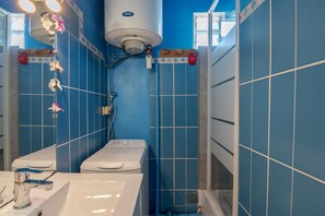 Un bagno con un WC bianco, un lavandino e uno spazio doccia.