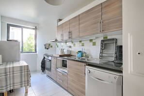 A modern kitchen with wooden cabinets, a built-in oven, and a dishwasher. - Le Havre Vincennes - Proche du Bois de Vincennes (Vincennes)