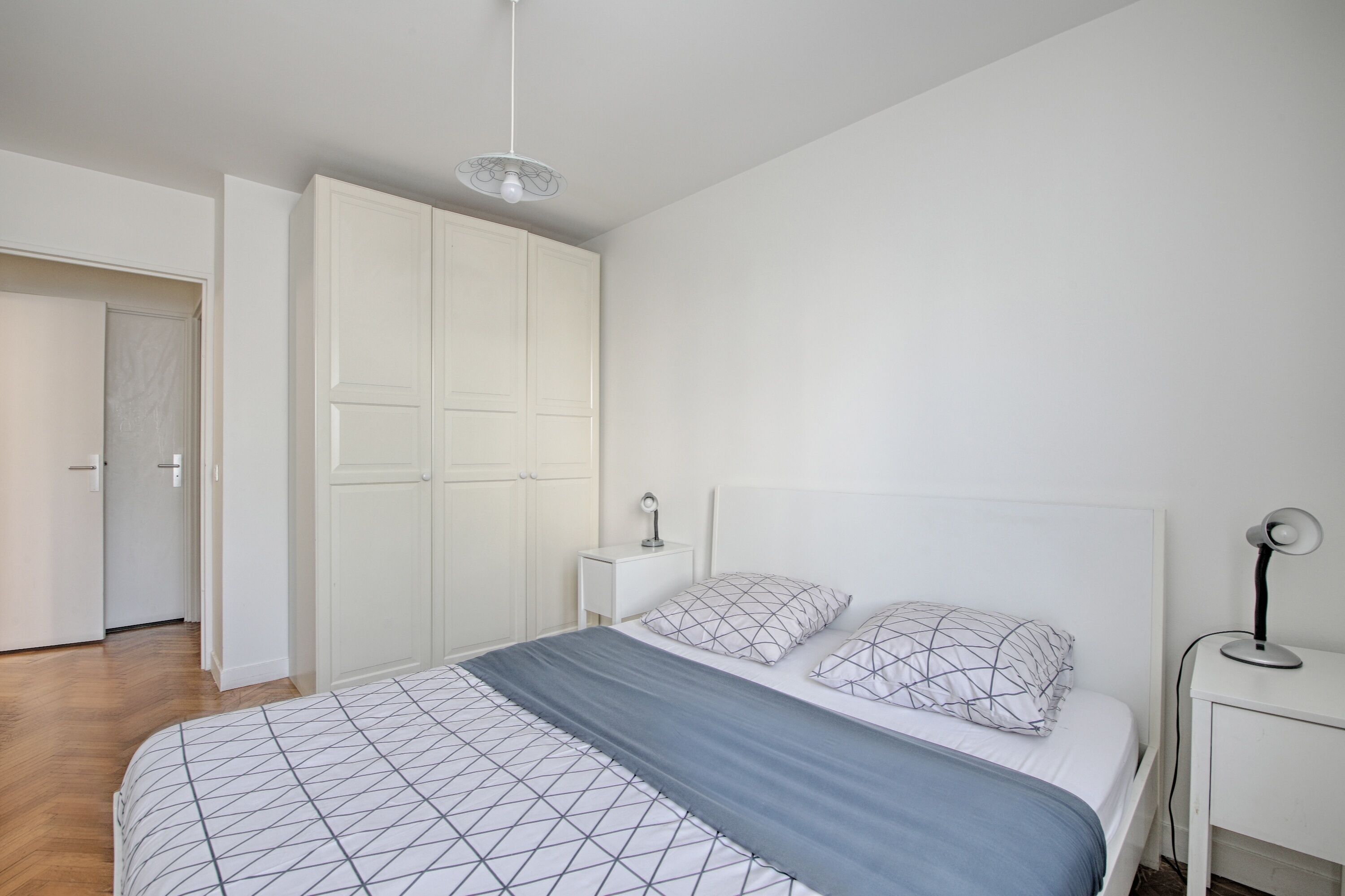 A bedroom with a bed, bedside tables, a wardrobe, and a ceiling fan.