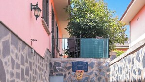 Ein kleiner Innenhof mit Kunstgrasanlage, einem Basketballkorb und einer Steinmauer.
