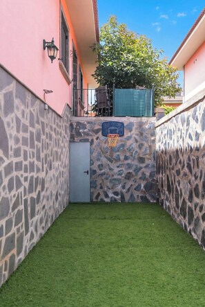 A small courtyard with artificial grass, a basketball hoop, and a stone wall. - Guest House El Rincón de Itara (Firgas)