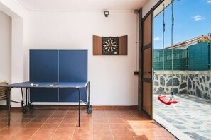 A room with a ping pong table, a dartboard, and a view of a swimming pool and outdoor area. - Guest House El Rincón de Itara (Firgas)