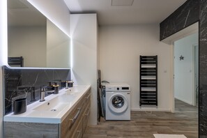 A modern bathroom with a large mirror, a washing machine, and a towel rack. - Le Beau Rivage - 1km de la Plage (Criel-sur-Mer)