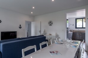 A modern kitchen with a dining area, white walls, and a view of the outdoors. - Le Beau Rivage - 1km de la Plage (Criel-sur-Mer)