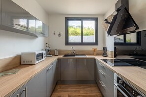 A modern kitchen with a central island, a microwave, a kettle, and a built-in oven. - Le Beau Rivage - 1km de la Plage (Criel-sur-Mer)