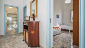A hotel room with a wooden cabinet, a mirror, a bed, and a bathroom visible through an open door. - Villa Le Terrazze Blu (Sicilia)