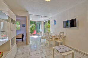 Una zona de menjador amb una taula, cadires i un televisor fixat a la paret.