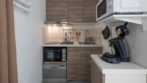 Eine kleine Küche mit Mikrowelle, Backofen und Kaffeemaschine.