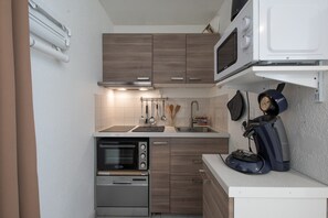 Eine kleine Küche mit Mikrowelle, Backofen und Kaffeemaschine.