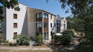 Ein mehrstöckiges Gebäude mit Balkonen, einer weißen Fassade und einem Garten mit einem Weg.