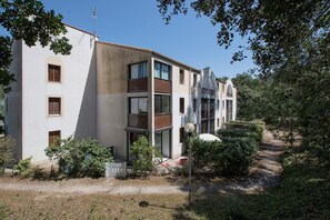 Ein mehrstöckiges Gebäude mit Balkonen, einer weißen Fassade und einem Garten mit einem Weg.