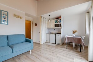 Ein gemütlicher, kompakter Wohnraum mit Sofa, Küchenzeile, Esstisch und einer kleinen Dekorationsvase.