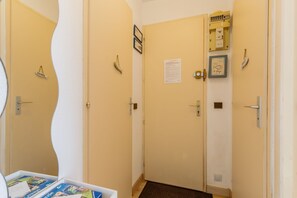 Un couloir avec une porte, une boîte électrique fixée au mur, un tableau encadré et un petit panneau.