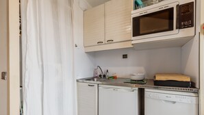 Een kleine keuken met een magnetron, een spoelbak en een vaatwasser.