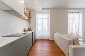 Uma cozinha moderna com armários cinzentos, bancada branca e piso de madeira.