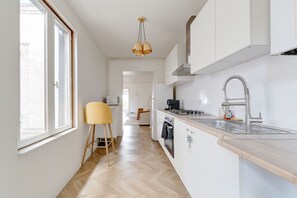 A modern kitchen with white cabinetry, a wooden countertop, and a stainless steel sink. - Le Cocon Champenois - Joli appt proche du centre (Reims)