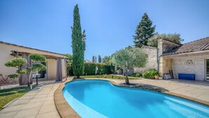 A swimming pool with a tiled deck, surrounded by trees and a building with a tiled roof. - La Maison Sarreau Martin - Entre Vignes et Nature (Gardegan-et-Tourtirac)