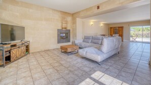A spacious living room with a large flat-screen TV, a fireplace, a sofa, and a ceiling fan. - La Maison Sarreau Martin - Entre Vignes et Nature (Gardegan-et-Tourtirac)