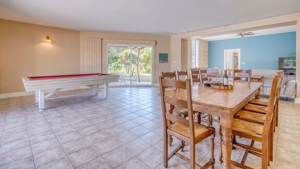A spacious dining area with a pool table, wooden chairs, and a view of the outdoors. - La Maison Sarreau Martin - Entre Vignes et Nature (Gardegan-et-Tourtirac)