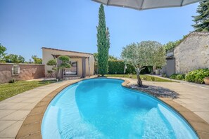 Ein Schwimmbecken mit geschwungener Kante, umgeben von einer gepflasterten Terrasse.