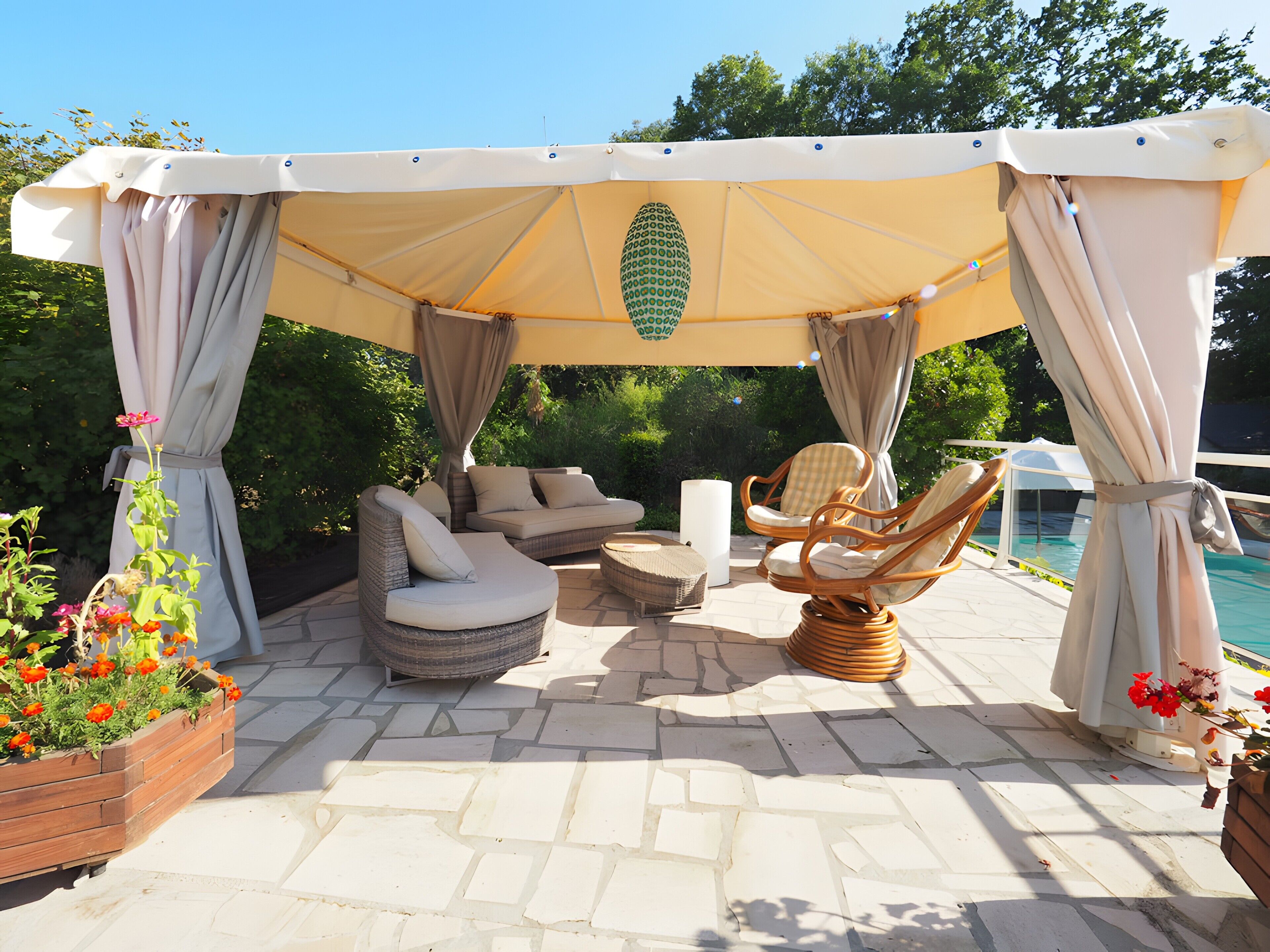 A covered outdoor seating area with a pool in the background.