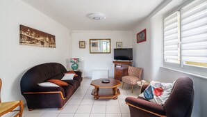 Una sala de estar con sofá, sillón, mesa de centro y televisor.