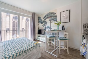 Ein Schlafzimmer mit Bett, Schreibtisch, Stuhl, Fenster und einer Wand mit einem Baumgemälde.