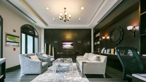 Eine moderne Lobby mit einer Chandelier, einer Sitzecke, einem Fernseher und Bücherregalen.