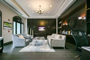 Eine moderne Lobby mit einer Chandelier, einer Sitzecke, einem Fernseher und Bücherregalen.