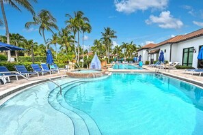 A pool with lounge chairs and umbrellas, surrounded by palm trees and a clear sky. - Oversized Residence 3BR Near 5th Avenue & Beach @ C104 (Naples)