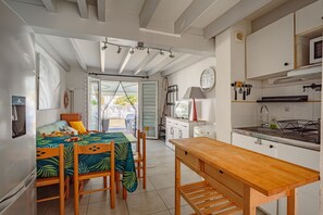 A compact kitchen with a dining area, a bed with a view, and a small kitchenette. - La Croisiere - À 1 km de l'aéroport (Anglet)