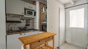 Pieni, käytännöllinen keittiö, jossa on puinen pöytä, mikroaaltouuni ja pesuallas.