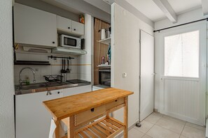 Eine kleine Küche mit einem Holztisch, einer Mikrowelle und einem Spülbecken.