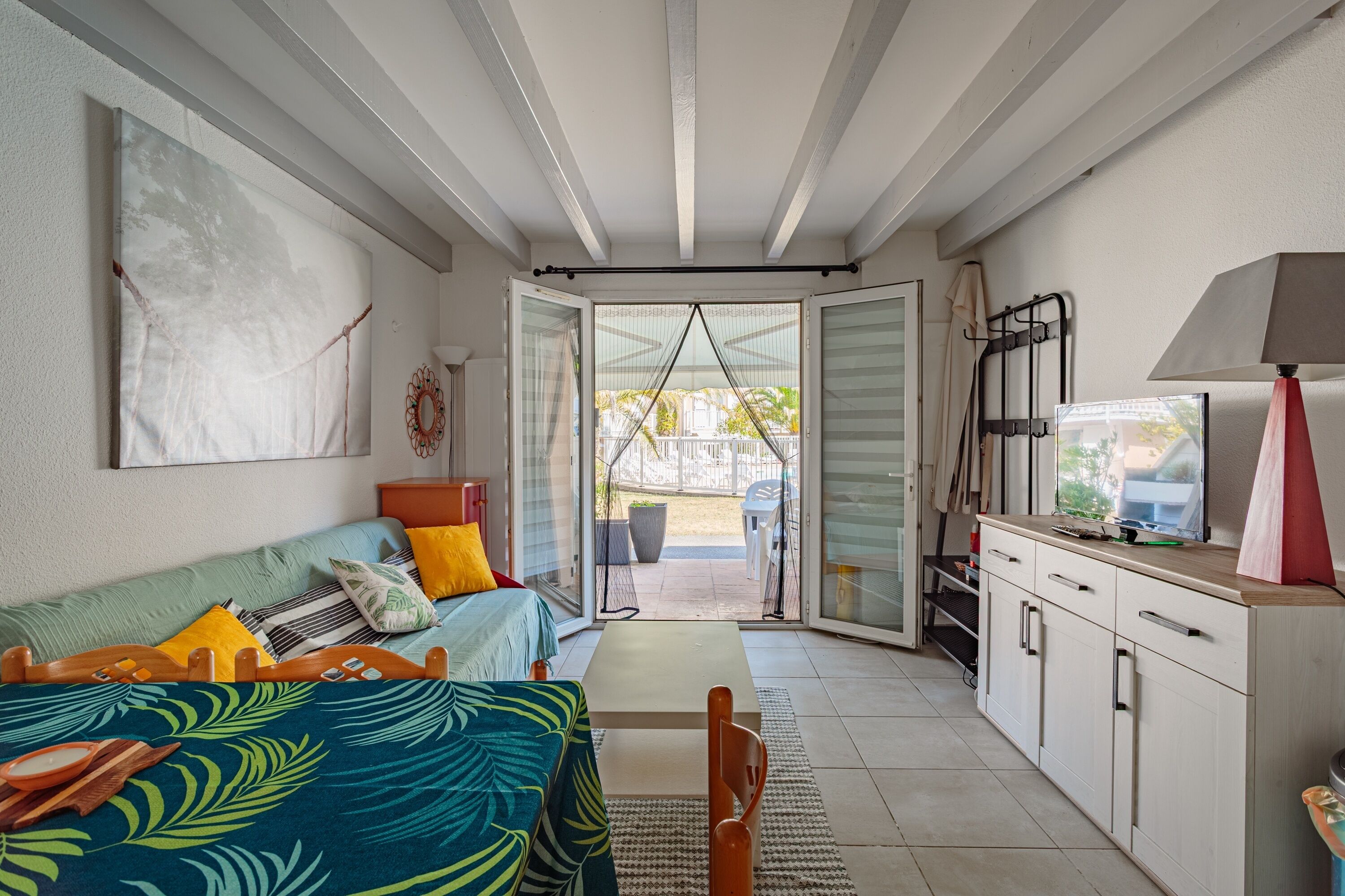 Een compacte kamer met een bed, een kleine kitchenette en een schuifdeur naar een buitenruimte.