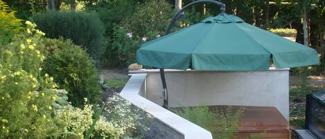 A garden with a patio area, a green umbrella, and various plants.