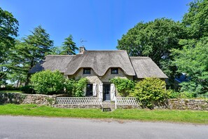 A stone cottage with a thatched roof, a white picket fence, and a stone wall. - Ty Crugo - Jolie maison familiale avec jardin (Saint-Lyphard)