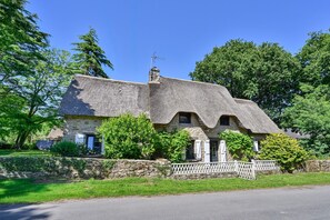 A stone house with a thatched roof, a white picket fence, and a stone wall. - Ty Crugo - Jolie maison familiale avec jardin (Saint-Lyphard)