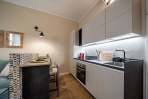 Eine kompakte Küche mit Einbauofen, Spüle und Arbeitsplatte mit Wasserkocher und Toaster.