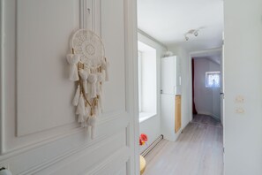 A hallway with a dreamcatcher on the wall, a window, and a door leading to another room. - L’éclat de Baccarat - Maison cosy en triplex (Baccarat)