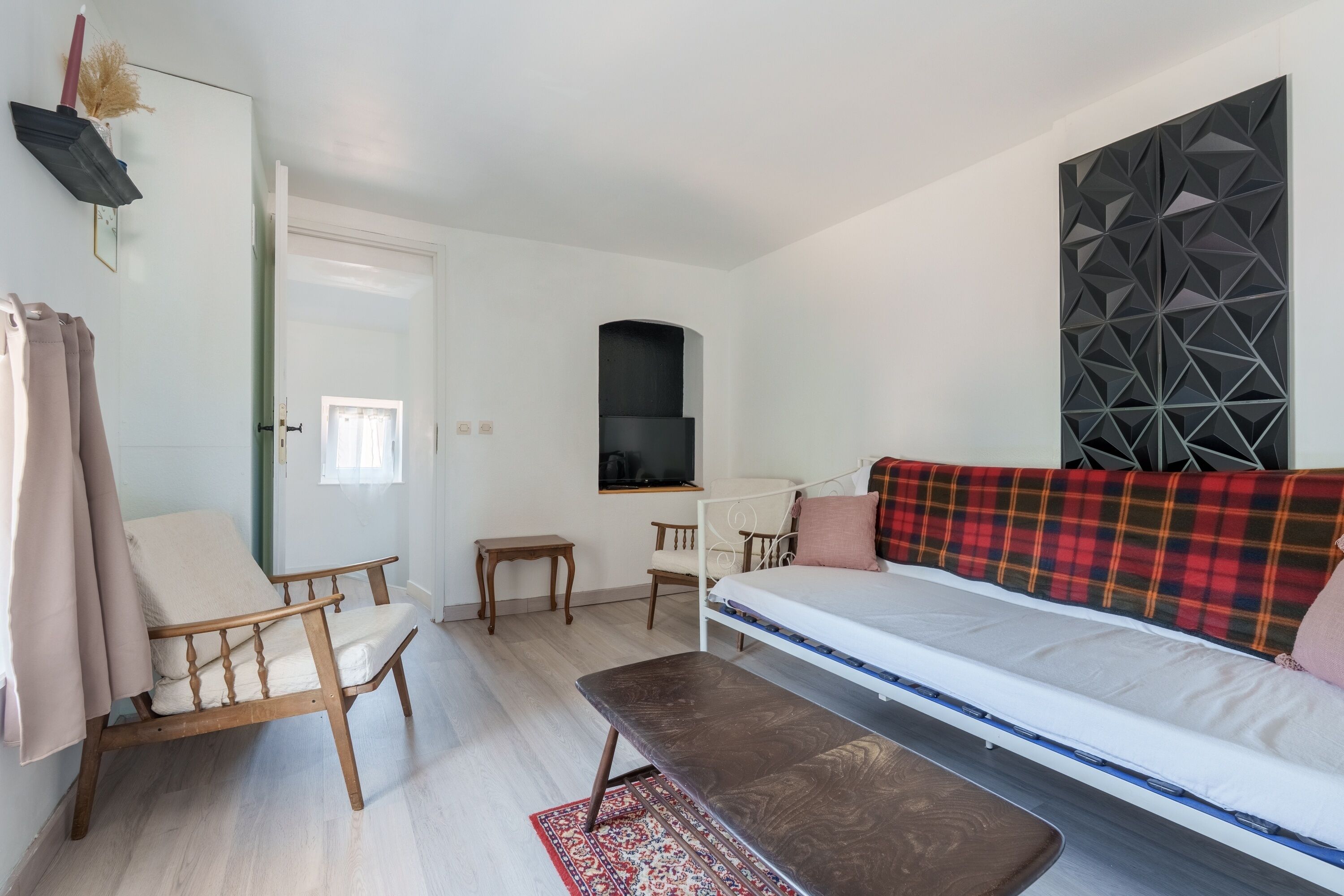 A modern room with a bed, a bench, a chair, a small table, and a TV.
