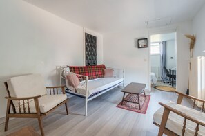 En moderne stue med sofa, stole, et lille bord og en tæppe med et mønster.