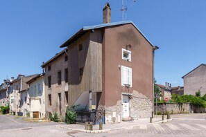 A two-story building with a brown facade, a visible chimney, and a small window with shutters. - L’éclat de Baccarat - Maison cosy en triplex (Baccarat)