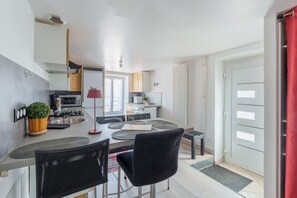 Et moderne køkken med spiseplads, inklusiv et bord, stole og en rød gulvlampe.