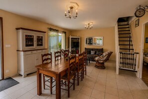 Ein Essbereich mit Holztisch und -stühlen, eine Küche mit Backofen, eine Treppe und eine Wanduhr.