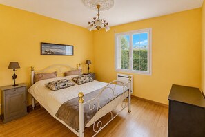 Ein Schlafzimmer mit Bett, Nachttischen, einem Fenster und einer Chandelier.