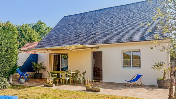A single-story house with a tiled roof, a patio with outdoor furniture, and a small garden area.