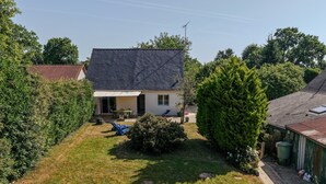 A residential property with a sloped roof, a covered patio, and a well-maintained lawn.
